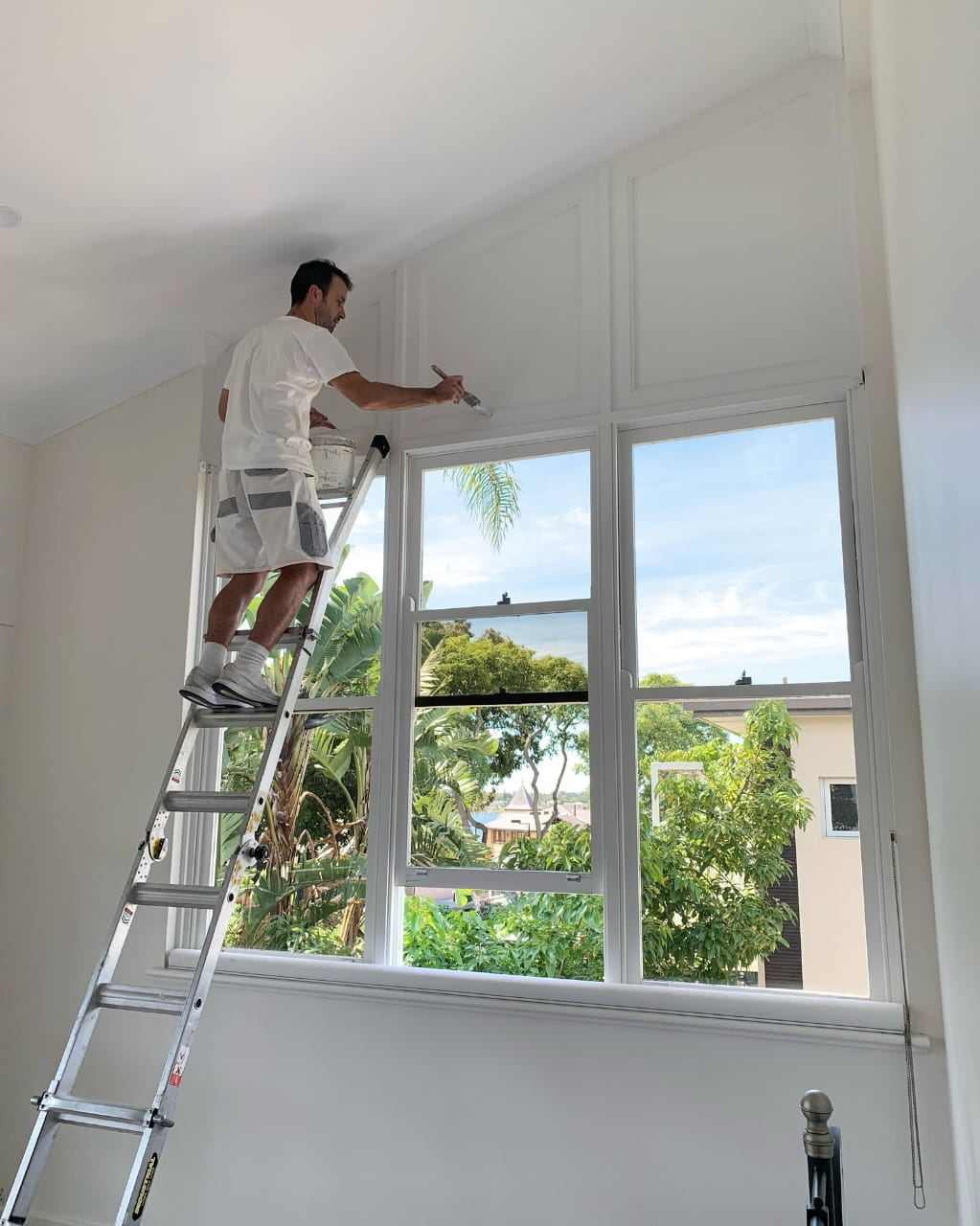 A Team Member of Pro Painting Works Painting a window on a Ladder